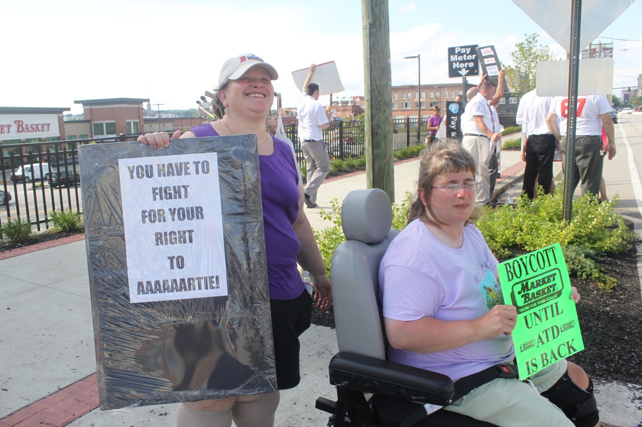 Hollie Kraatz, left, and sister Leah Kraatz, hold signs in support of ousted CEO Arthur T. DeMoulas.
