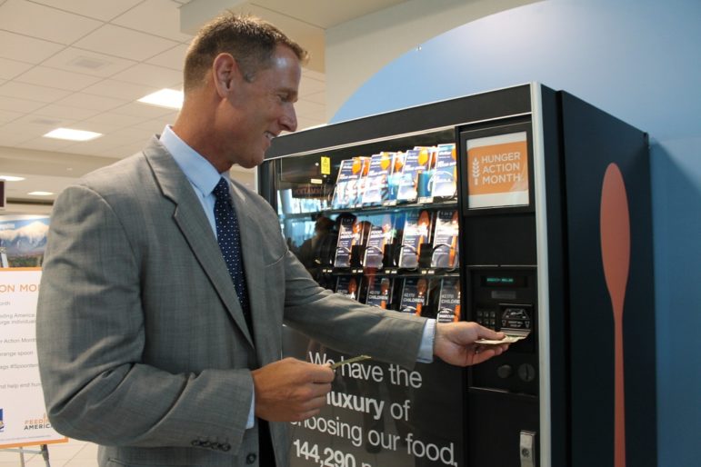  J. Brian O’Neill, Deputy Director of the Manchester-Boston Regional Airport, purchases an orange spoon in support of Hunger Action Month this September. 