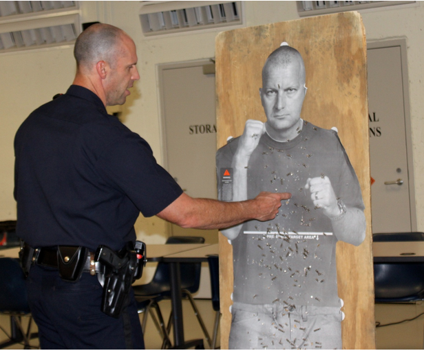 Officer Paul Rondeau talks to Citizens Academy members about target practice using a cardboard "target man" cutout.