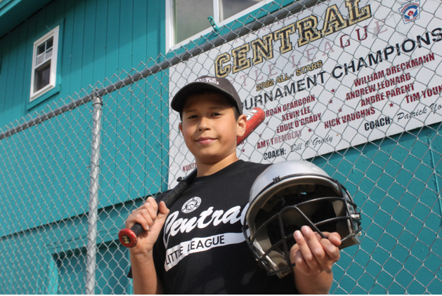Michael Negron, 12, shows off some of the donated equipment from Project Play, which has helped supplement the team's equipment budget.