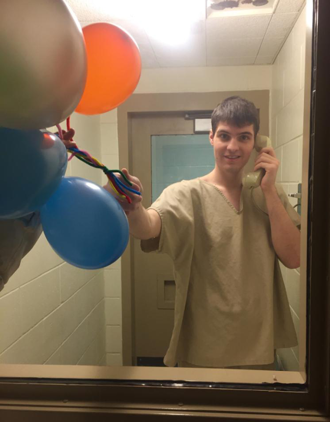 Corey Peterson, through the glass partition visiting area at the Secure Psychiatric Unit at New Hampshire State Prison for Men in Concord. His mother, Shelly Peterson Raza, blew up the balloons and held them up on the visitors' side to make it appear he was holding the balloons to celebrate his birthday Jan. 30. She texted the photo to a relative before guards confiscated her cell phone. Corey has not been charged with a crime.