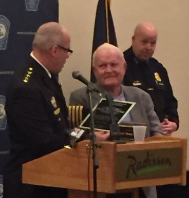 Chief Nick Willard reads a plaque to Denny O'Neil for 45 years of service as a bail commissioner.