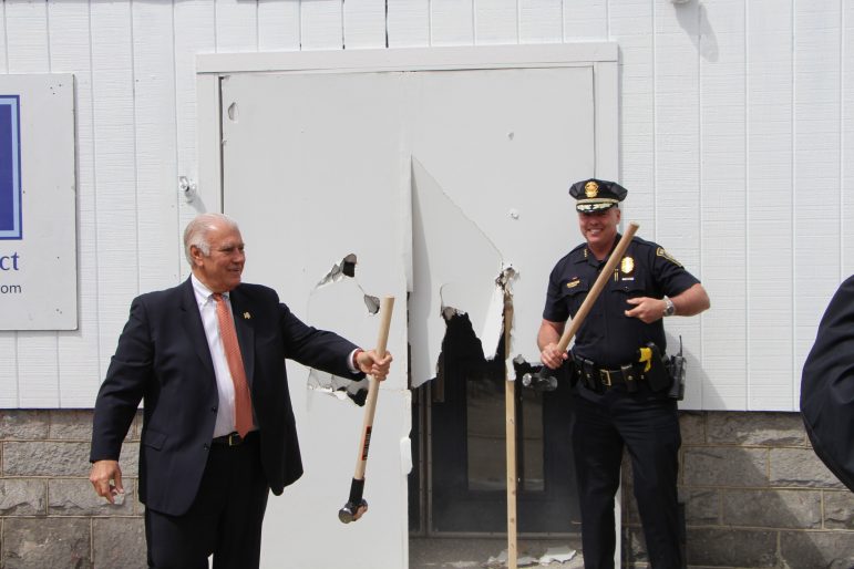 Manchester Mayor Ted Gatsas and Manchester Police Chief Nick Willard break through the entrance of MPAL’s Michael Briggs Community Center to celebrate the kickoff of Building on Hope’s Build Week 2016.