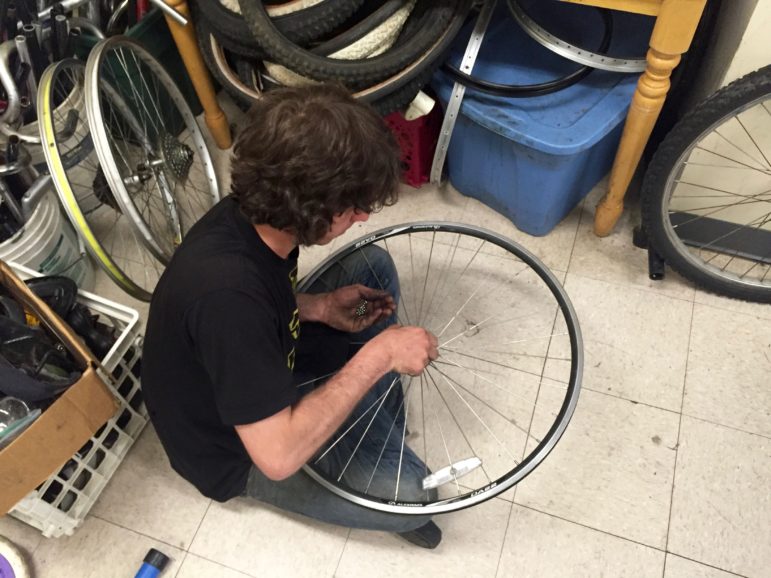 Wes Wiggins adds some ball bearings to a bike wheel hub.