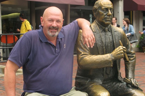 Journalist Roger Carroll is pictured with statue of Red Auerbach in Boston.