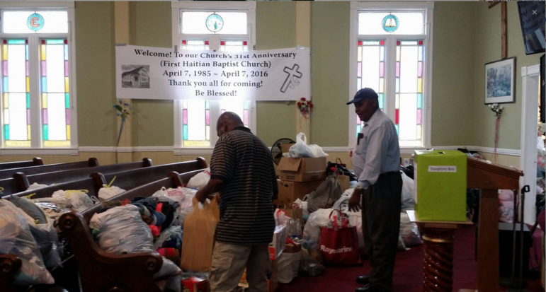 Pastor Remand Dumont of First Haitian Baptist Church in the sanctuary with a parishioner where items are being collected to send to Haiti in the aftermath of Hurricane Matthew.