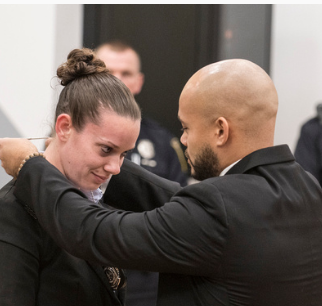 Officer Stephanie Kooharian receives her badge from her fiance, Mathens Figueroa.