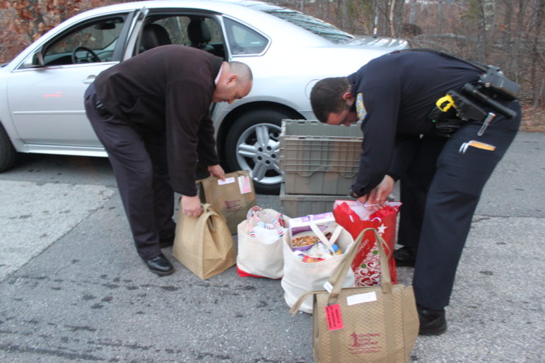 Nashua Police Capt. Jay Maloney, left, and Officer Brandon Cali, go over the goods before heading out for deliveries in Nashua.
