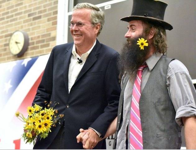 Jeb Bush holds hands with Rod Webber after receiving flowers of peace on the campaign trail.