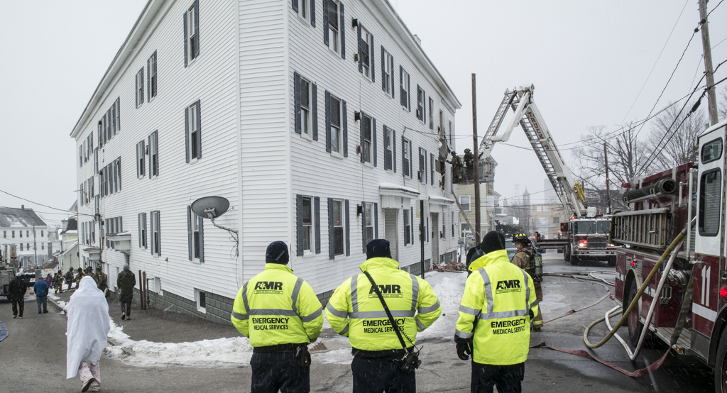 AMR first responders stand by while Manchester Fire crews knock down a fire at 297 Concord Street on Saturday.