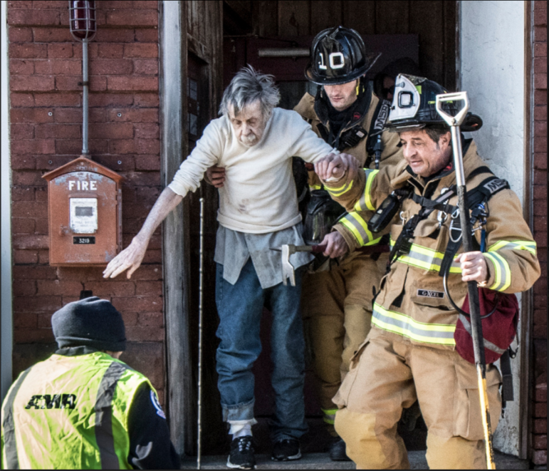 Fire crews assist a resident of 480 Chestnut St. from the building during a Sunday morning fire.