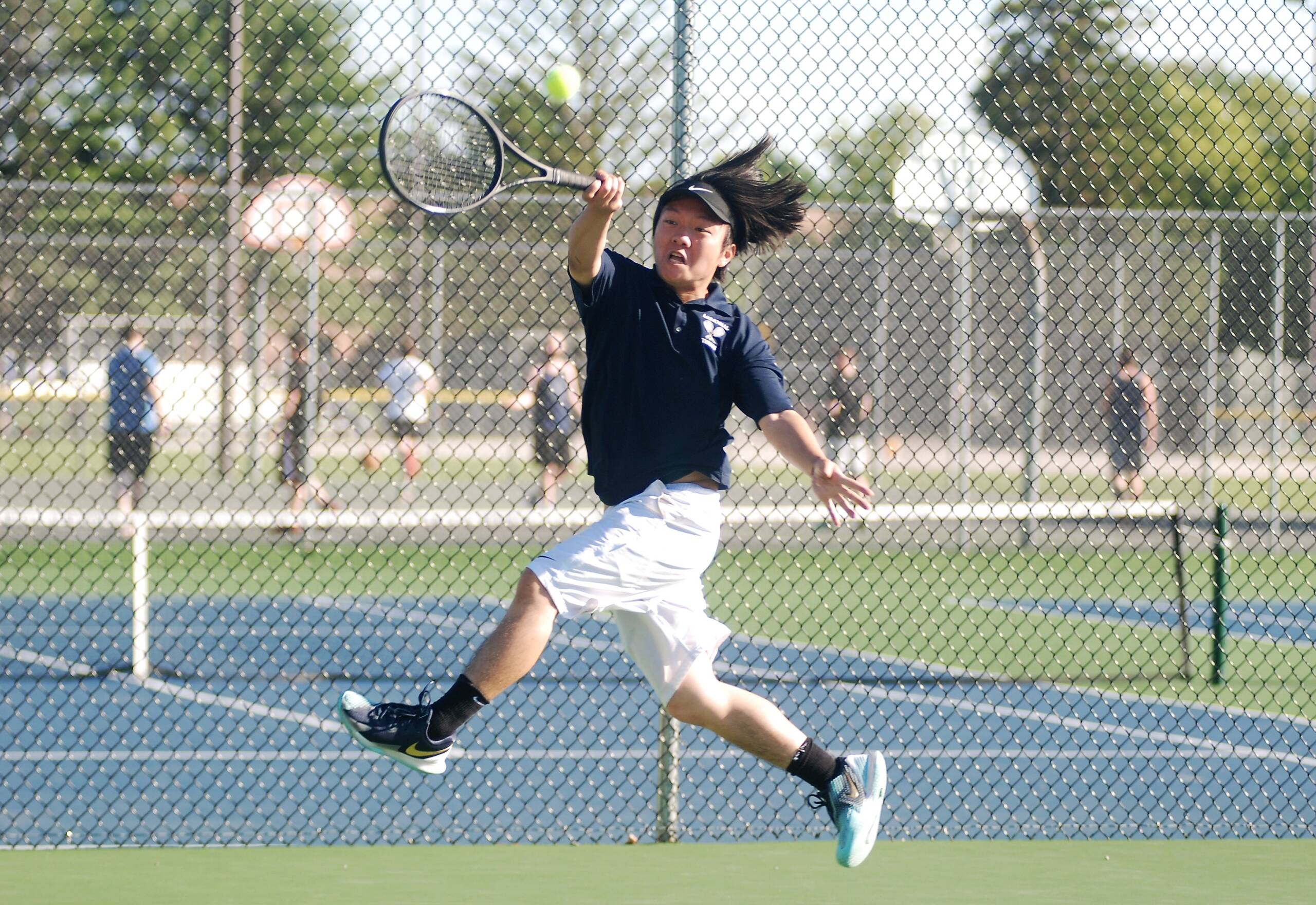 Todd Tran stretching to hit the tennis ball.